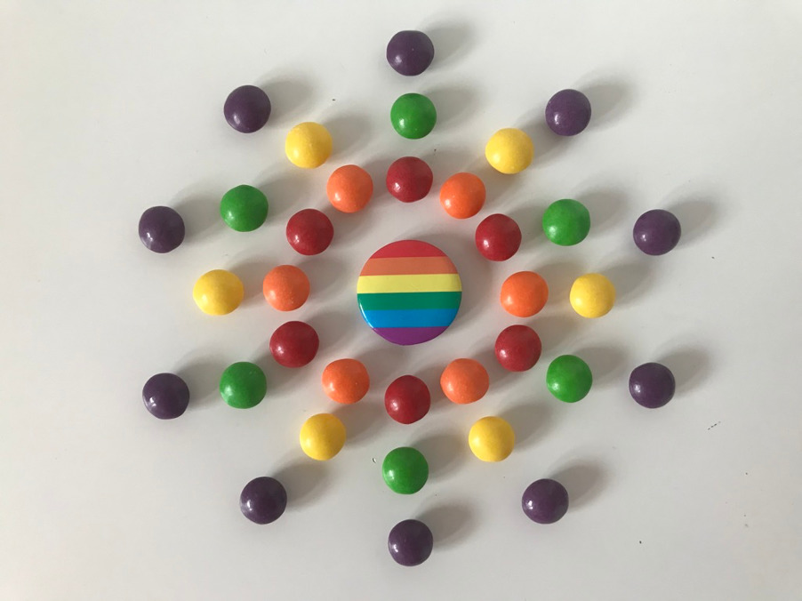 Skittles in the rainbow colours surrounding a rainbow badge