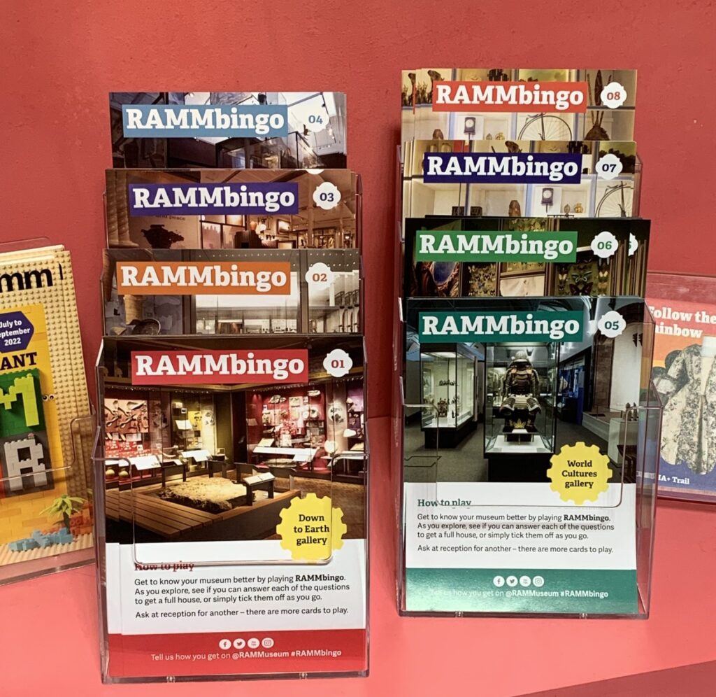 6 different a5 RAMMBingo cards in plastic stands, against a pink background. 