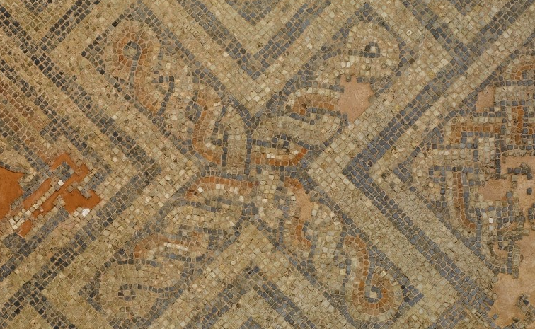 a close up detail of a Roman mosaic, showing small blue/grey, white and brown tiles forming the shape of an X