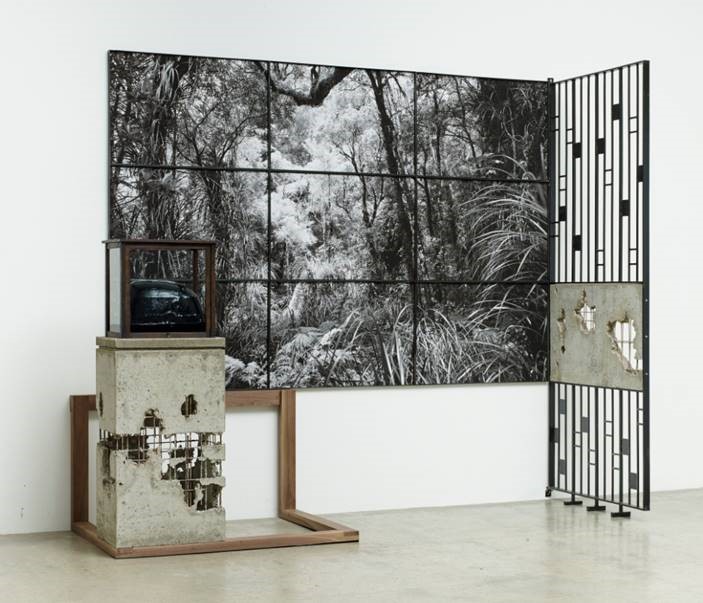 A photographic artwork of a forest, with sculptural elements framing it