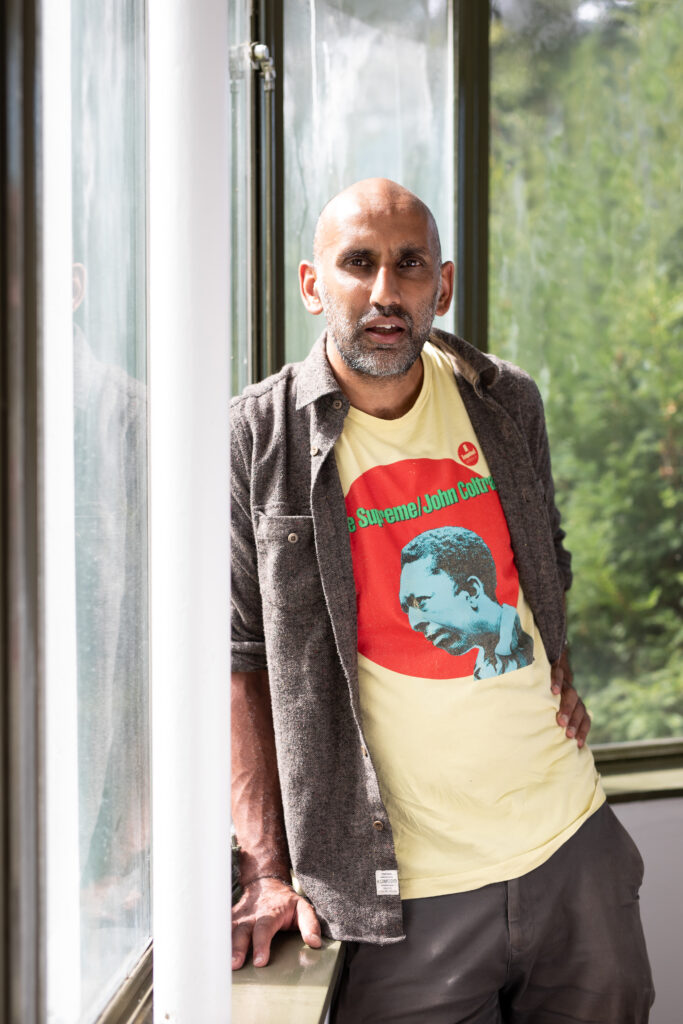 a portrait of the artist Ashish Ghadiali, standing next to a window