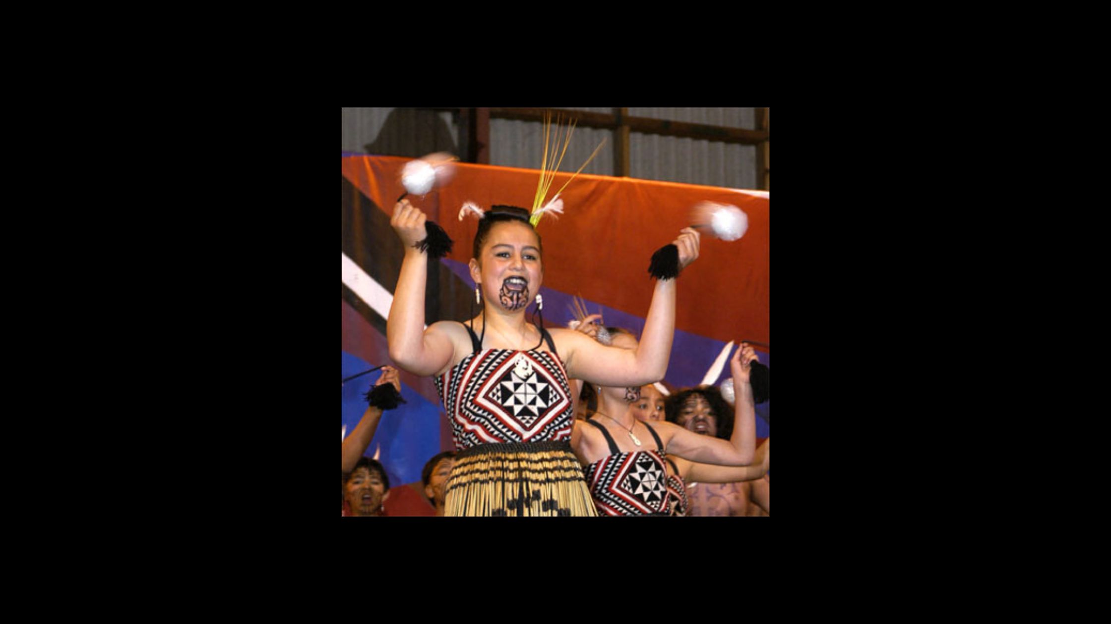 a woman holding poi sticks with Maori facial tattoos and traditional Maori dress