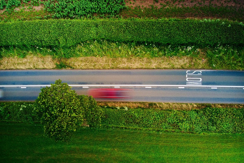 photo: a streak of red as a car speeds down a country road