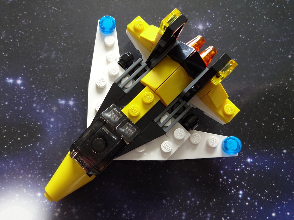 a small space vessel made from Lego bricks, sat on a star filled background