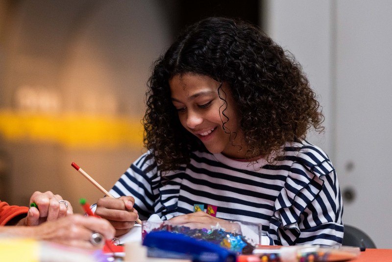 a girl smiles as she colours something in at a crafts table