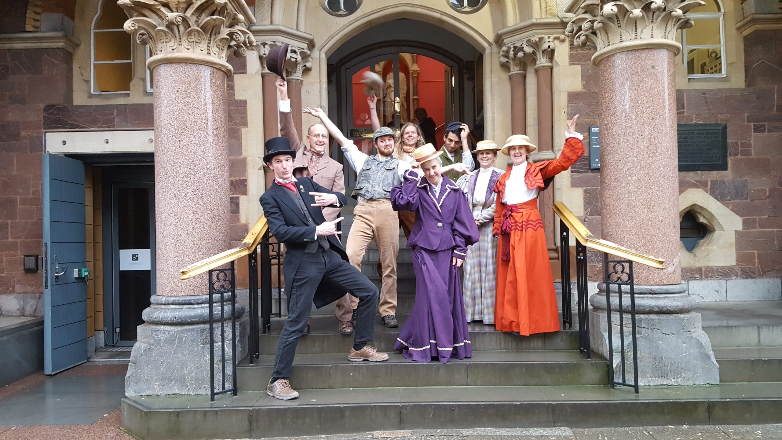 Photo of people dressed as historical characters, wearing Victorian era dresses, tombola hats and top hats.