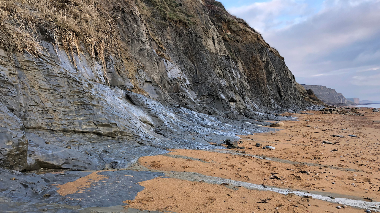 the base of a cliff, with red sand