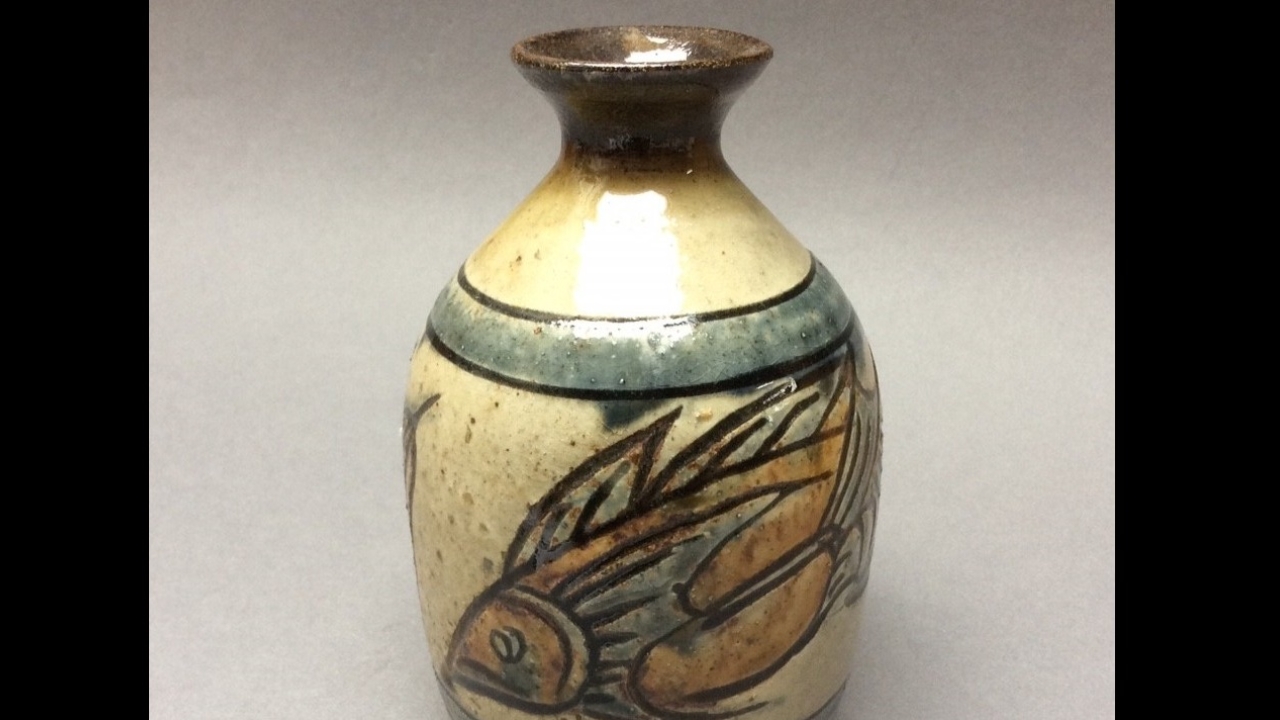 a clay vase with a small spout opening decorated with a fish