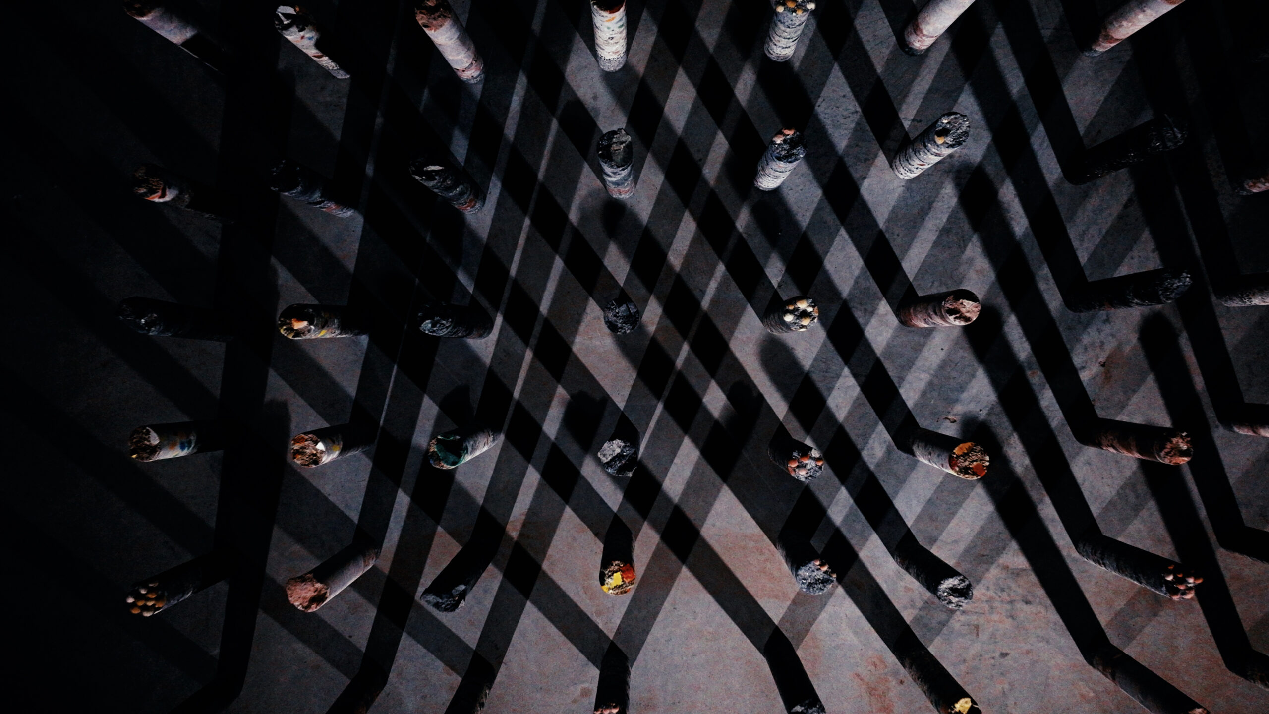 A close-up image of data cables sticking out of a concrete surface. The ends have been roughly sliced off. The shadows of the cables create a hatched/crisscross pattern